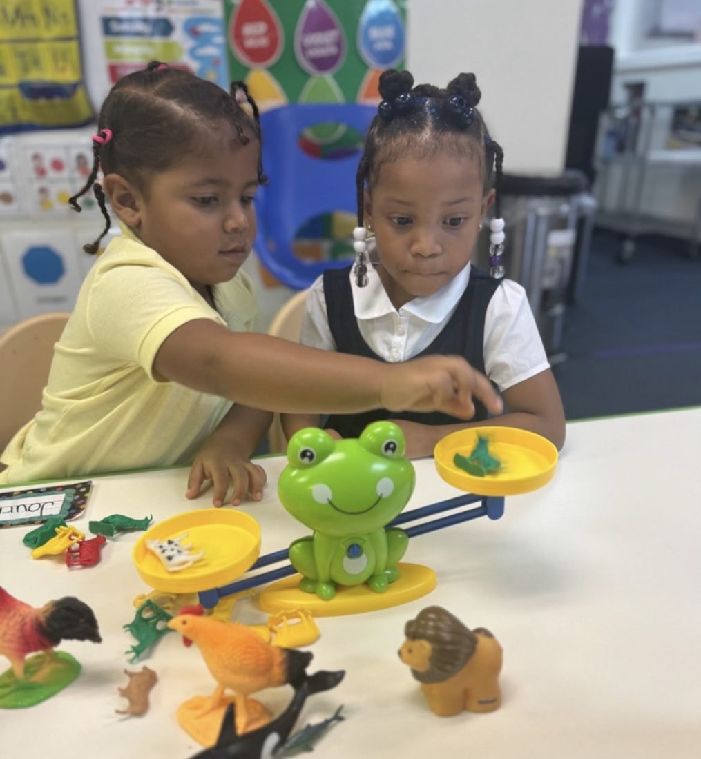 Pre-K scholars using a balance scale during a STEM activity